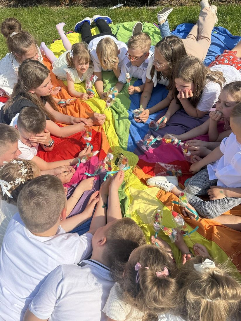 Radosne dzieci bawiące się na kolorowej chuście animacyjnej